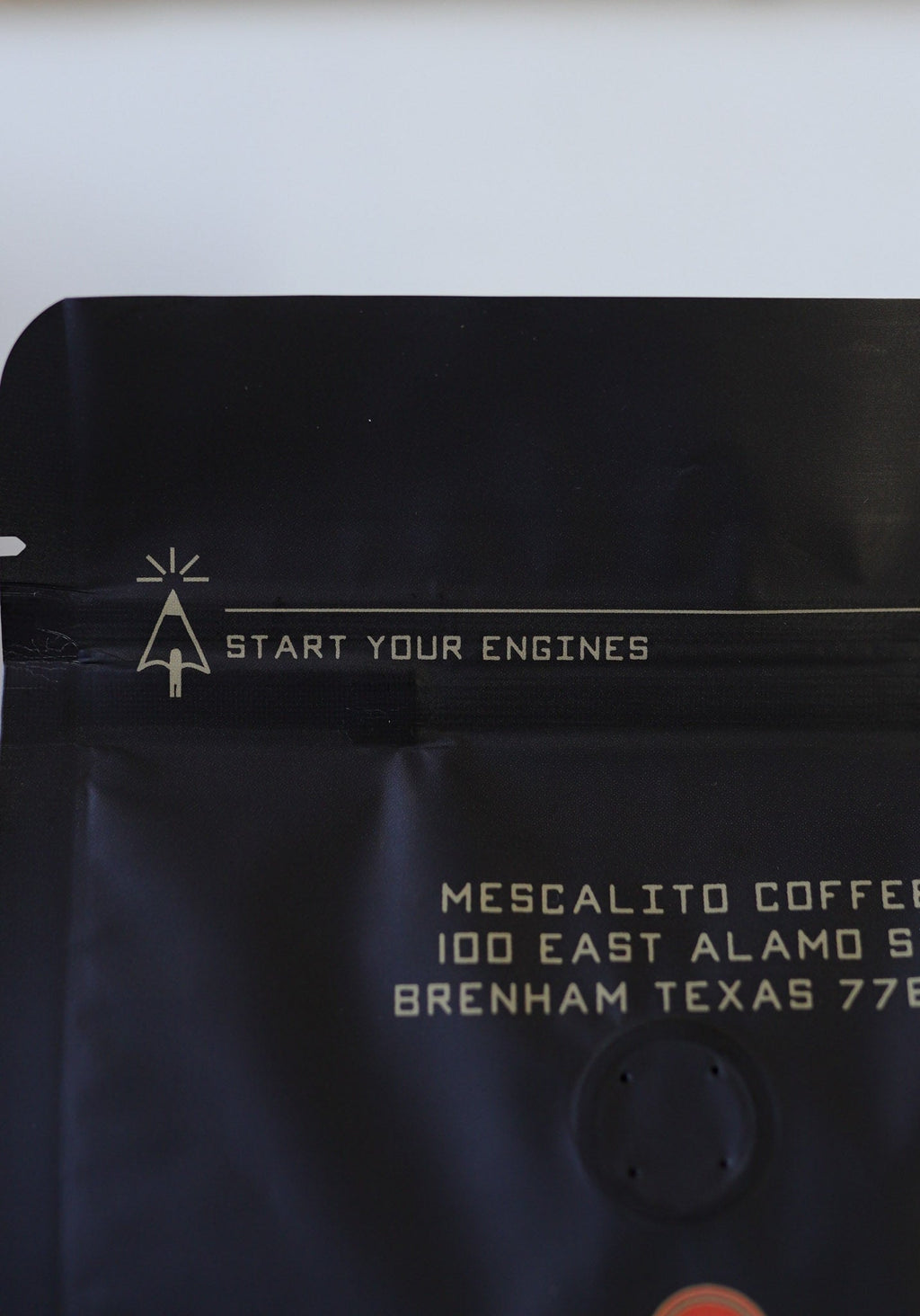 The “START YOUR ENGINES” black coffee bag from Mescalito Coffee features their Brenham, Texas address and contains Single Origin Whole Coffee Beans—Chelchele—a vibrant Ethiopian medium roast made with the anaerobic natural process.
